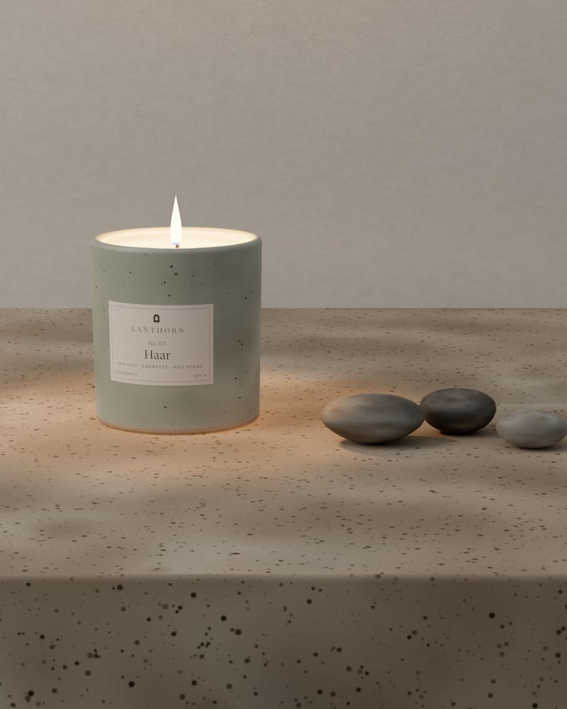 Haar on a stone windowsill in soft daylight, with three grey pebbles lined up beside it.